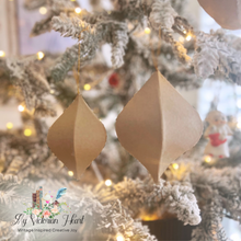 Load image into Gallery viewer, Two paper ornaments in two varied sizes hanging on a decorated flocked Christmas tree with warm string lights.