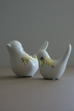 Load image into Gallery viewer, Two white ceramic bird figurines with gold foil leaf and acorn designs, standing on a neutral surface against a gray background.