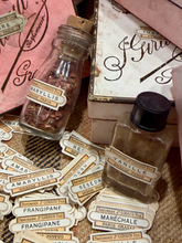 Load image into Gallery viewer, Two vintage-style perfume bottles labeled Marvillis and Vanille, surrounded by matching decorative labels and a pink box on a textured surface.