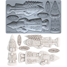Load image into Gallery viewer, A mold tray and example cutouts for IOD Belsnickel Christmas ornaments, featuring a fish, gnome, Saint Nick, and holiday words like Joul, Noël, and Yule in a light gray and off-white color scheme.