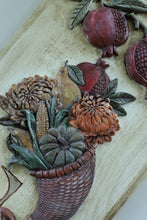 Load image into Gallery viewer, A close-up of a carved decorative wall piece showing a harvest basket filled with corn, pumpkins, gourds, and leaves, alongside pomegranates, on a light wood background.