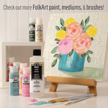 Load image into Gallery viewer, FolkArt paint bottles with a floral painting on a easel against a white paneled wall.