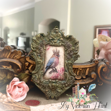 Load image into Gallery viewer, Crowned Bird perched on pink roses in handpainted aged moss green frame with cherubs