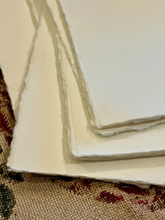 Load image into Gallery viewer, Close-up of a stack of white paper sheets on a textured fabric background