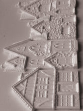 Load image into Gallery viewer, White embossed plastic or resin decorative pieces shaped like houses and cottages, shown on a plain light background.