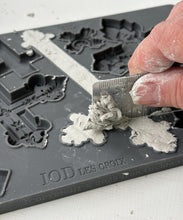 Load image into Gallery viewer, Person using a tool to level air dry clay in an 'IOD Les Croix' silicone mould. 