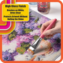 Load image into Gallery viewer, Person applying Mod Podge Diamond Top Coat to a diamond art project holding decoupage brush with Mod Podge bottle in background.