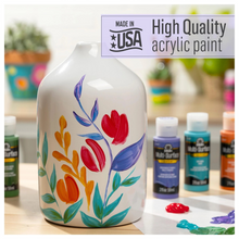 Load image into Gallery viewer, Decorative vase with floral design and acrylic paint bottles on a table.