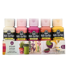 Load image into Gallery viewer, Set of FolkArt Multi-Surface acrylic paint bottles in various colors with a box in the background.