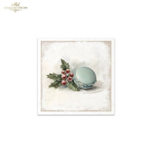 Load image into Gallery viewer, A square framed art print from Ash Collection featuring a light blue macaron with green holly leaves and red berries on a textured cream background.