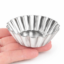 Load image into Gallery viewer, A small metallic silver fluted tart tin or cup, shown resting on a person's fingers against a plain white background.