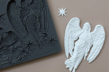Load image into Gallery viewer, A dark gray silicone mold with an embossed angel figure and star details, shown next to a white angel figurine and a small white star on a beige background.